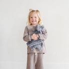 Child holding a gray elephant plush toy against a white background