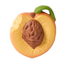 A novelty peach-shaped item, likely a chocolate or soap bar, featuring a textured brown pit in the center, a yellow-orange rind, and a green stem, with the brand name 'Oli & Carol' embossed on the side.