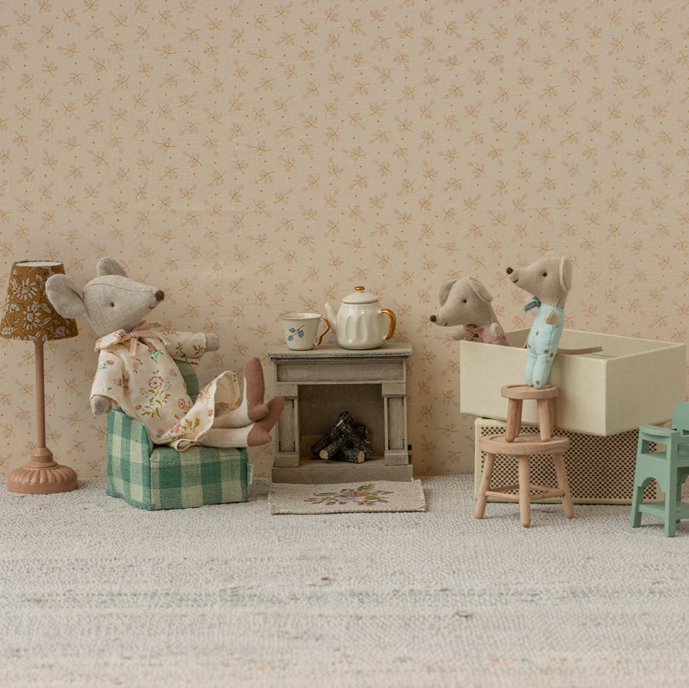 Miniature diorama with toy mice and furniture against a patterned wall.