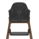Rear view of a high chair with a dark gray molded plastic seat and harness, supported by a medium brown wooden frame, on a solid white background.