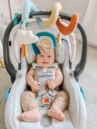 Baby in a car seat with colorful hanging toys