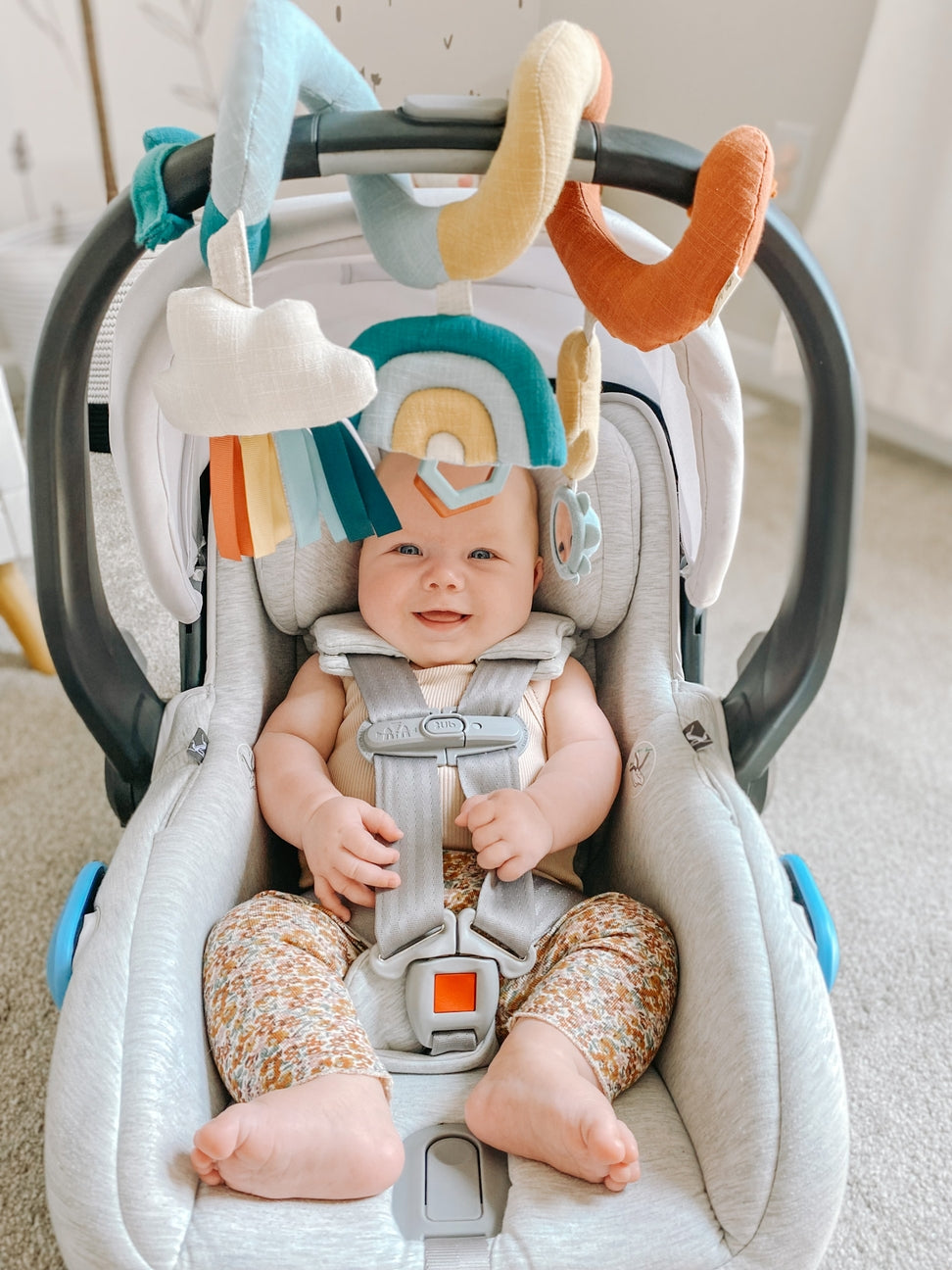 Baby in a car seat with colorful hanging toys