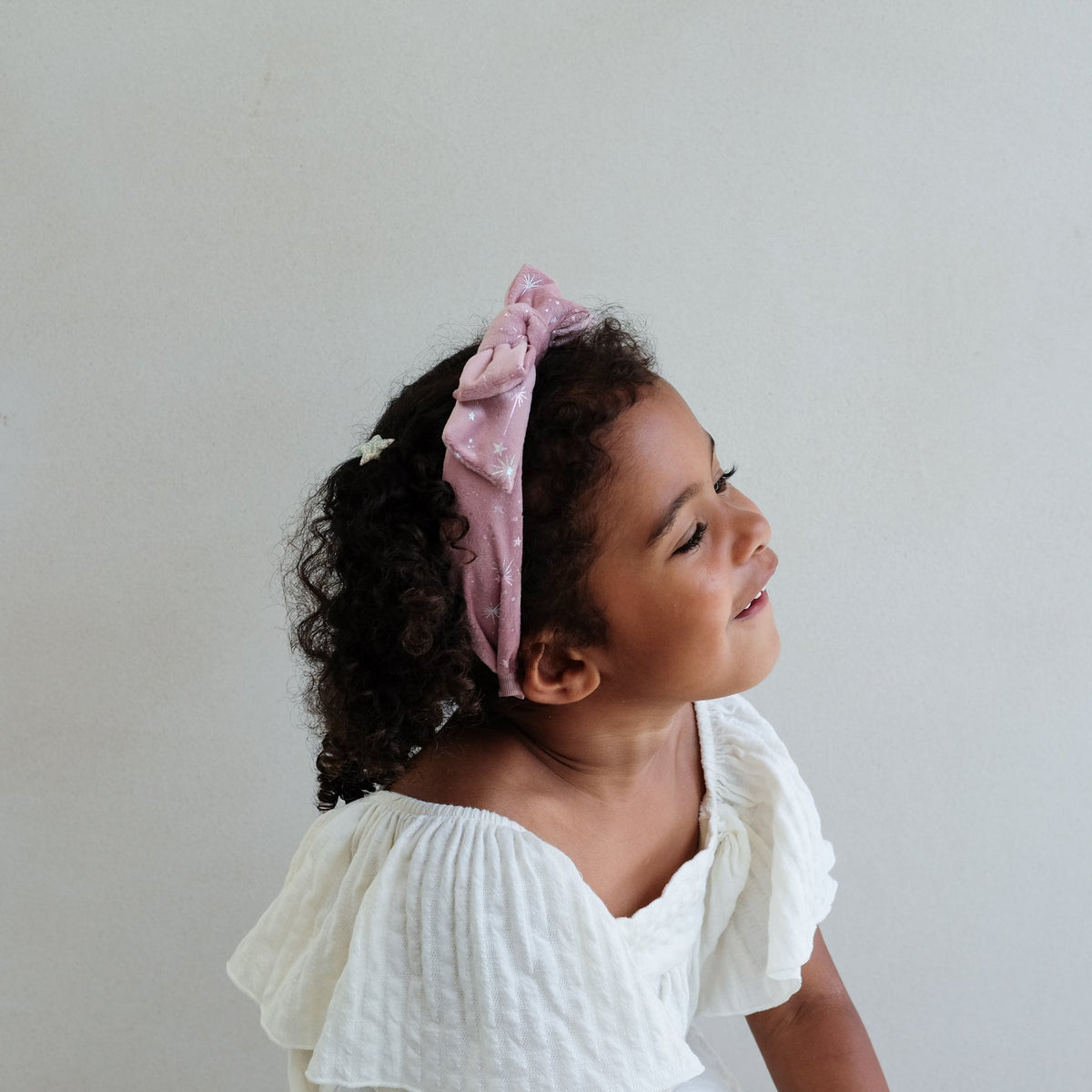 Child wearing a pink headband with a white background