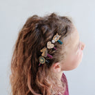 Child with decorated hair clips in their hair against a plain background