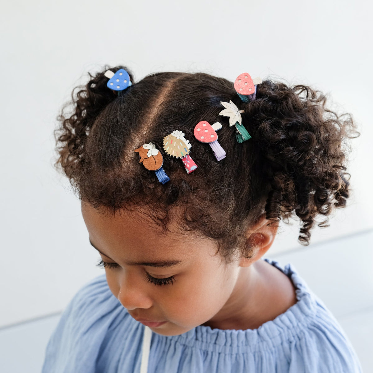Child with colorful hair clips in their hair against a light background