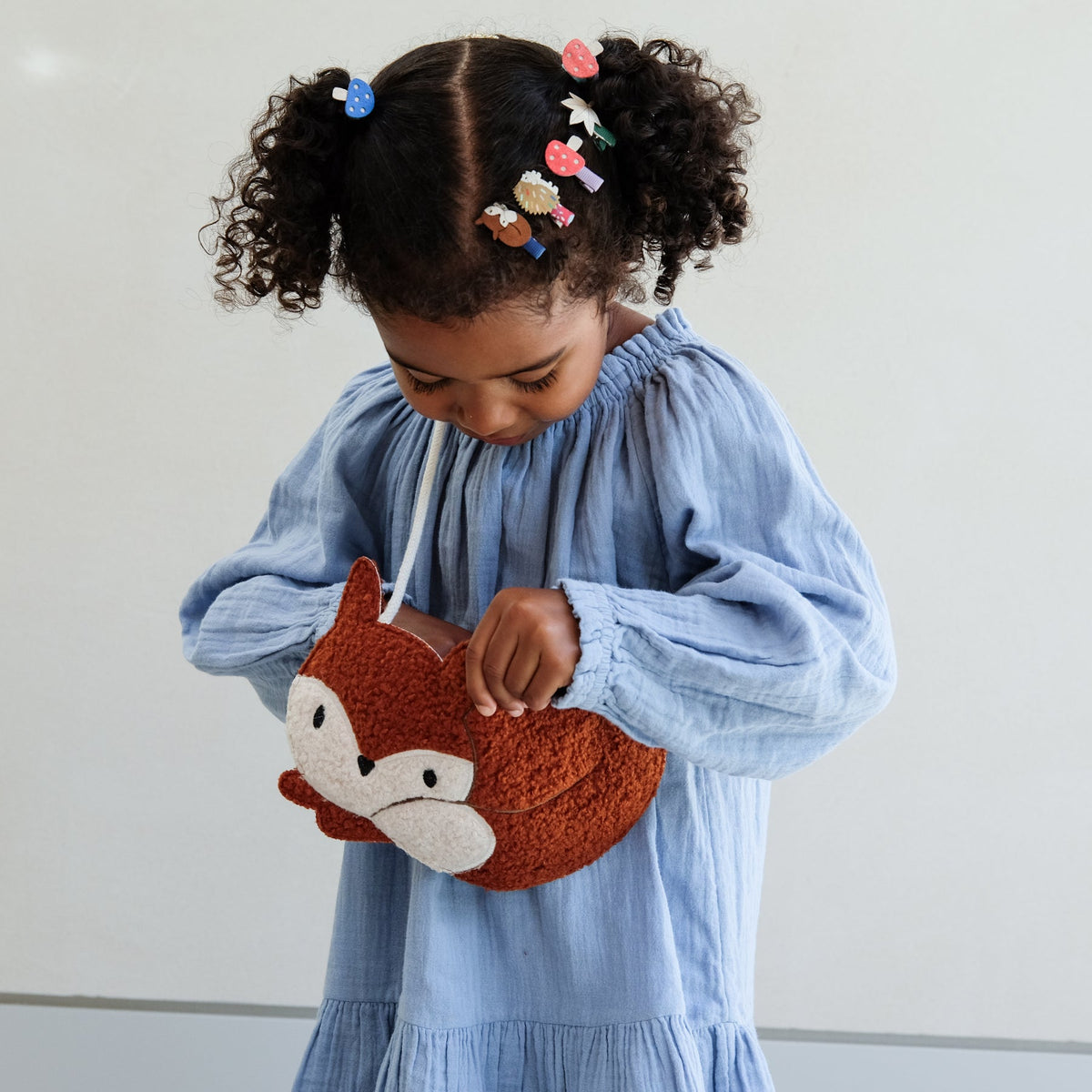 Child holding a fox-shaped pouch with a plain background