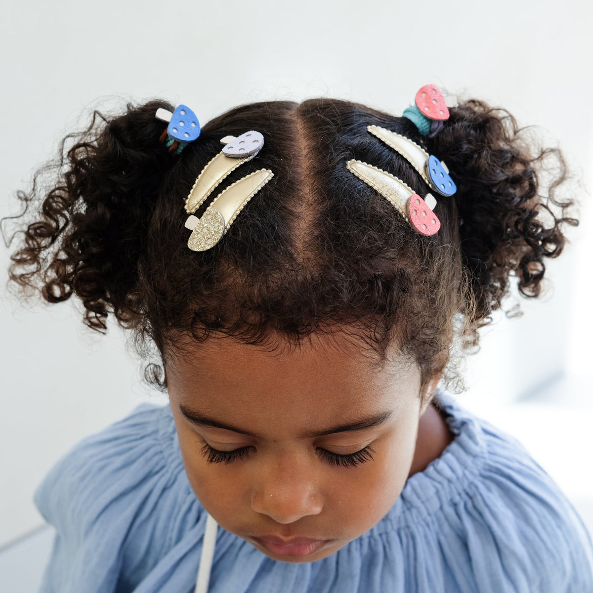 Child with styled hair featuring colorful hair clips against a light background