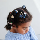 Child with styled hair wearing colorful hair clips against a light background