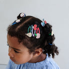 Child with colorful hair clips on a light background