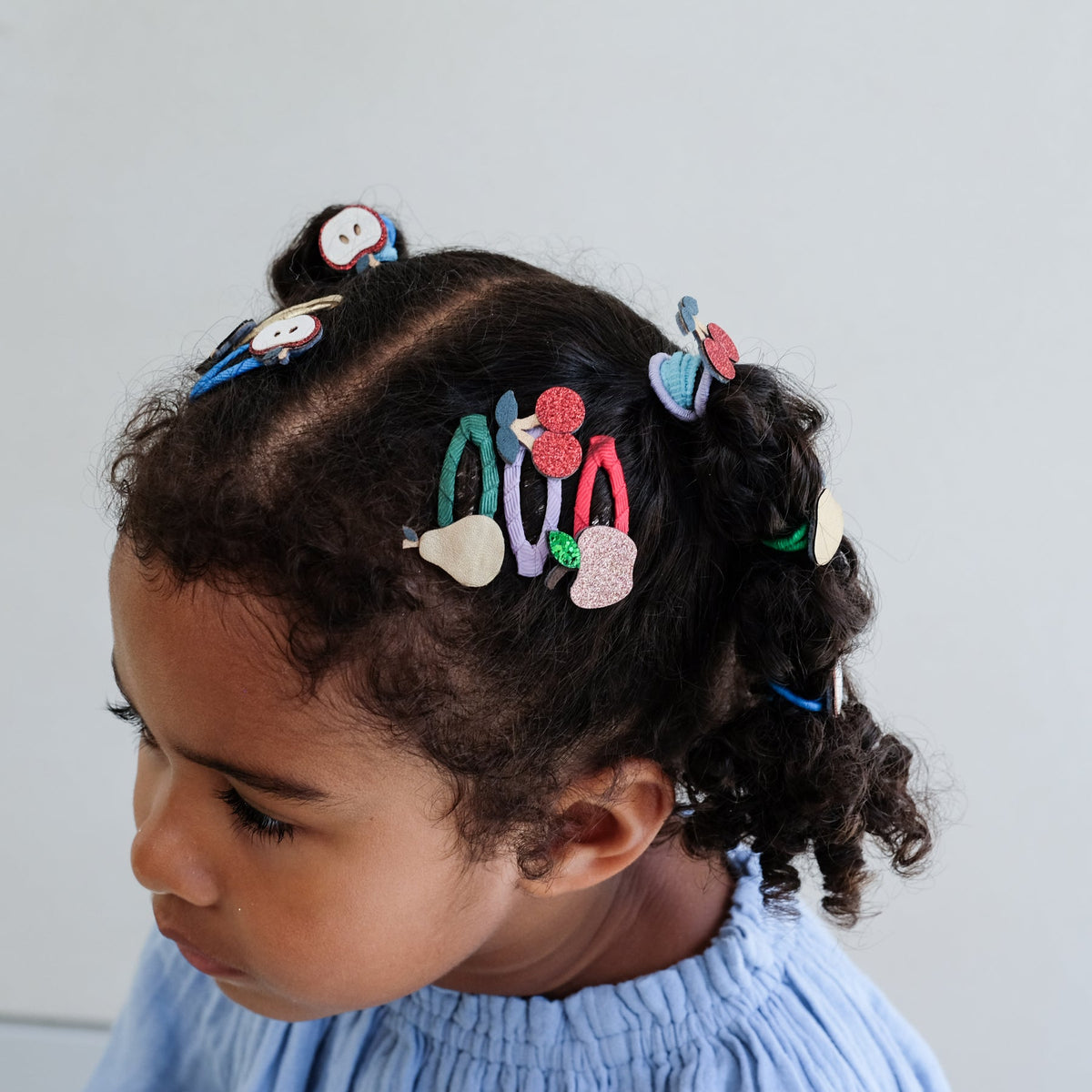 Child with colorful hair clips on a light background