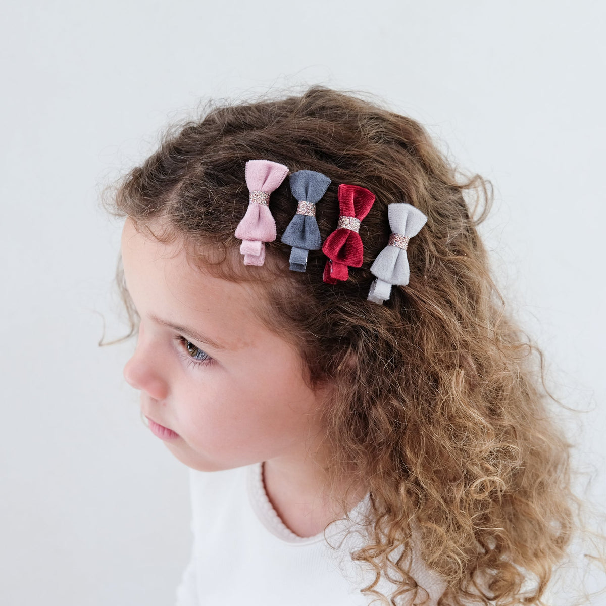 Child with colorful hair bows in their hair against a white background