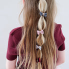 Person with long blonde hair styled in braids, wearing a maroon top on a white background
