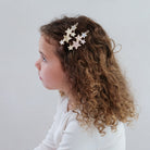 A girl wearing a set of star-shaped hair clips in various colors on a white background
