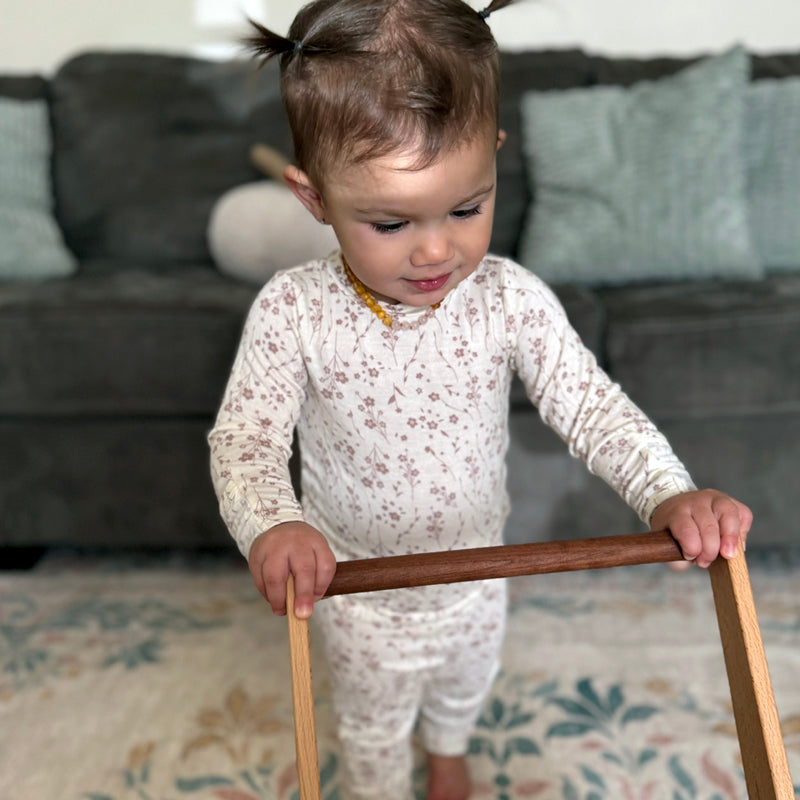 Child standing with a wooden walker in a living room setting