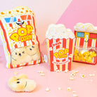 Popcorn-themed plush toys and packaging on a pink background