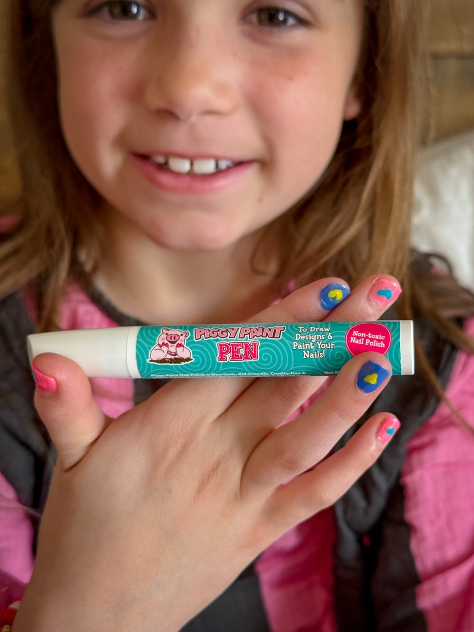 Child holding a colorful marker pen with a wooden background