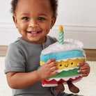 Child holding a plush toy cake with a candle