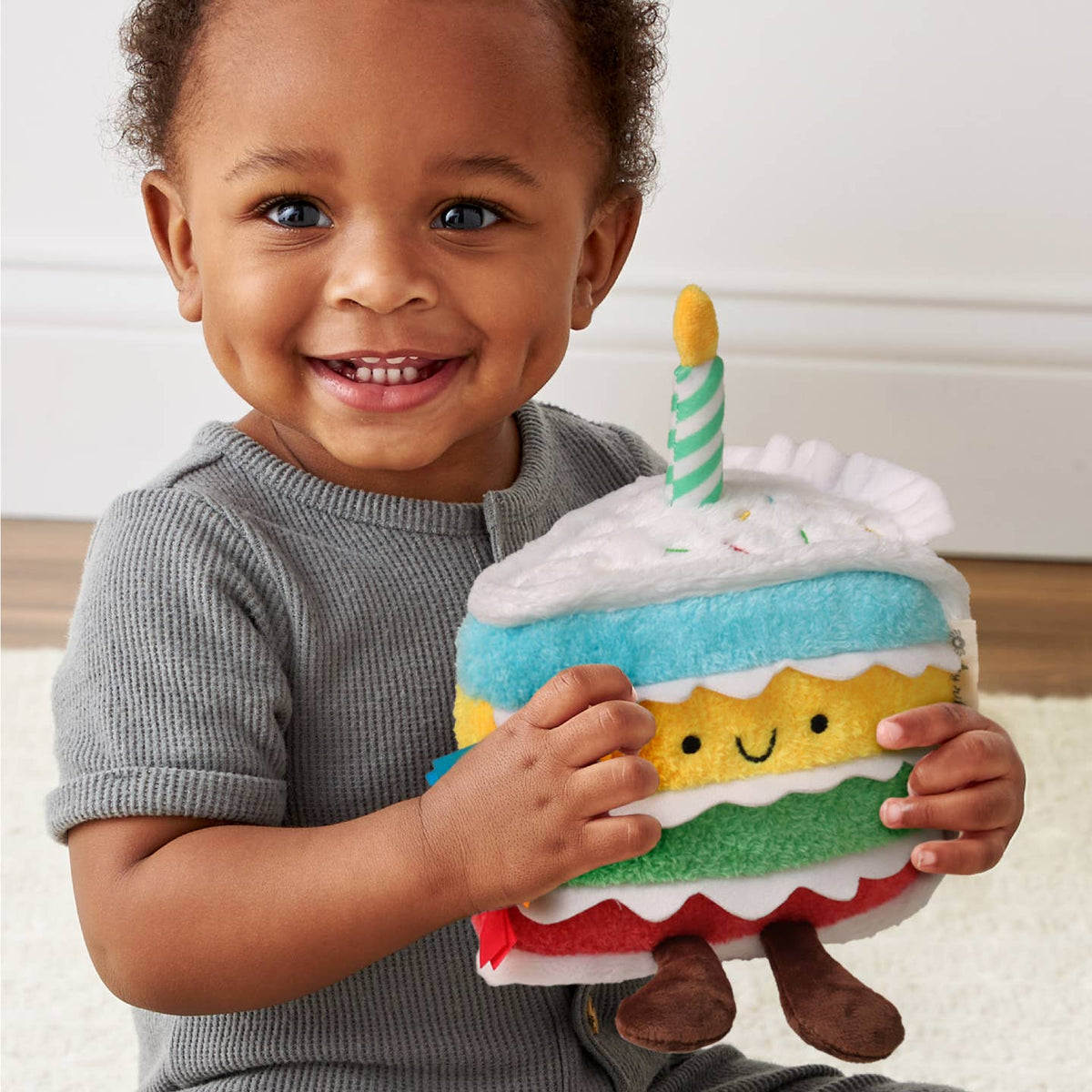 Child holding a plush toy cake with a candle