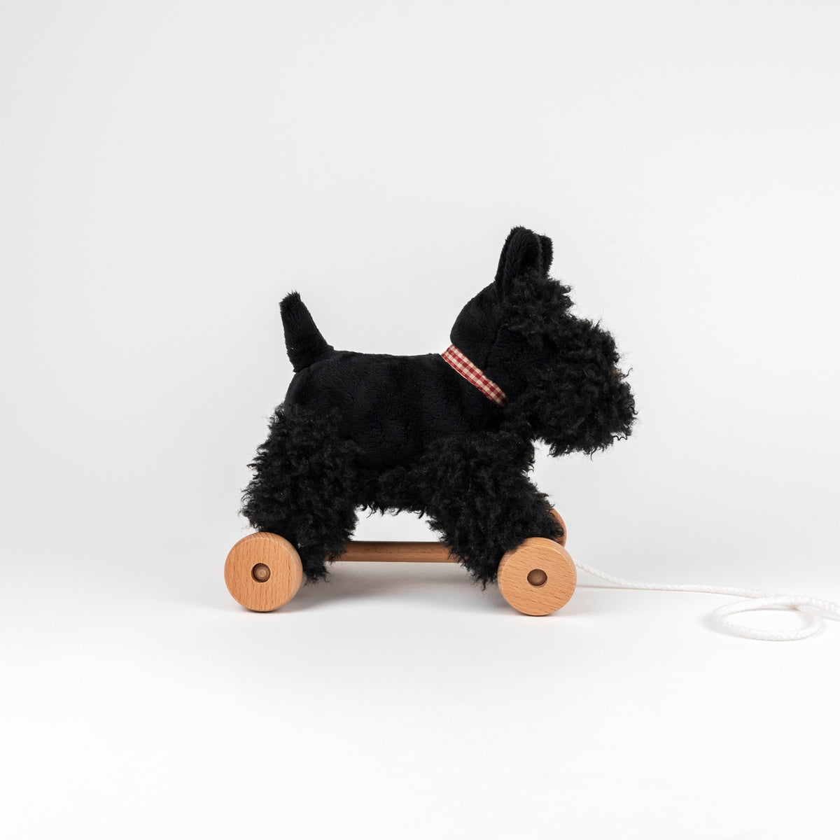 Black dog-shaped pull toy with wooden wheels on a white background