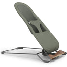 An adjustable baby support seat with an olive green padded cushion and a dark gray metal stand, shown on a clean white background.