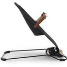 A modern black baby swing or bassinet with a curved metal stand, featuring a wooden headrest support with small red and white accents, shown against a plain white background.