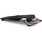 A black padded exercise or massage board with a black metal frame and a light brown wooden footrest, shown on a clean white background.