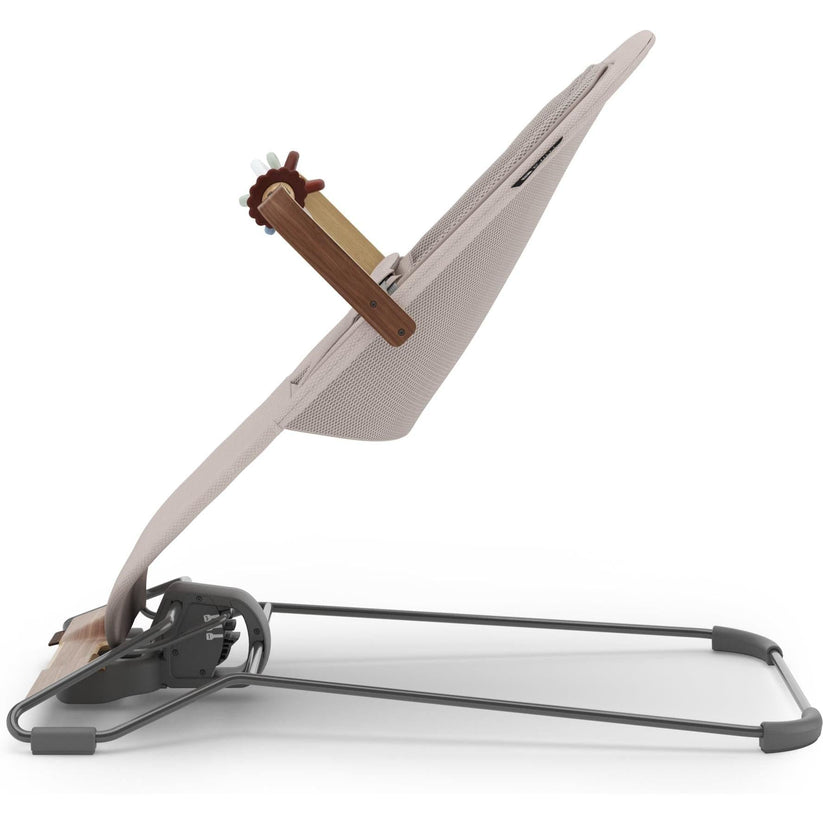 A modern baby swing or bouncer with a light beige mesh seat, a brown wooden support arm, and a dark gray metal base frame, shown on a clean white background.