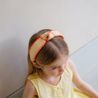 Young girl wearing a decorative headband with a plain background