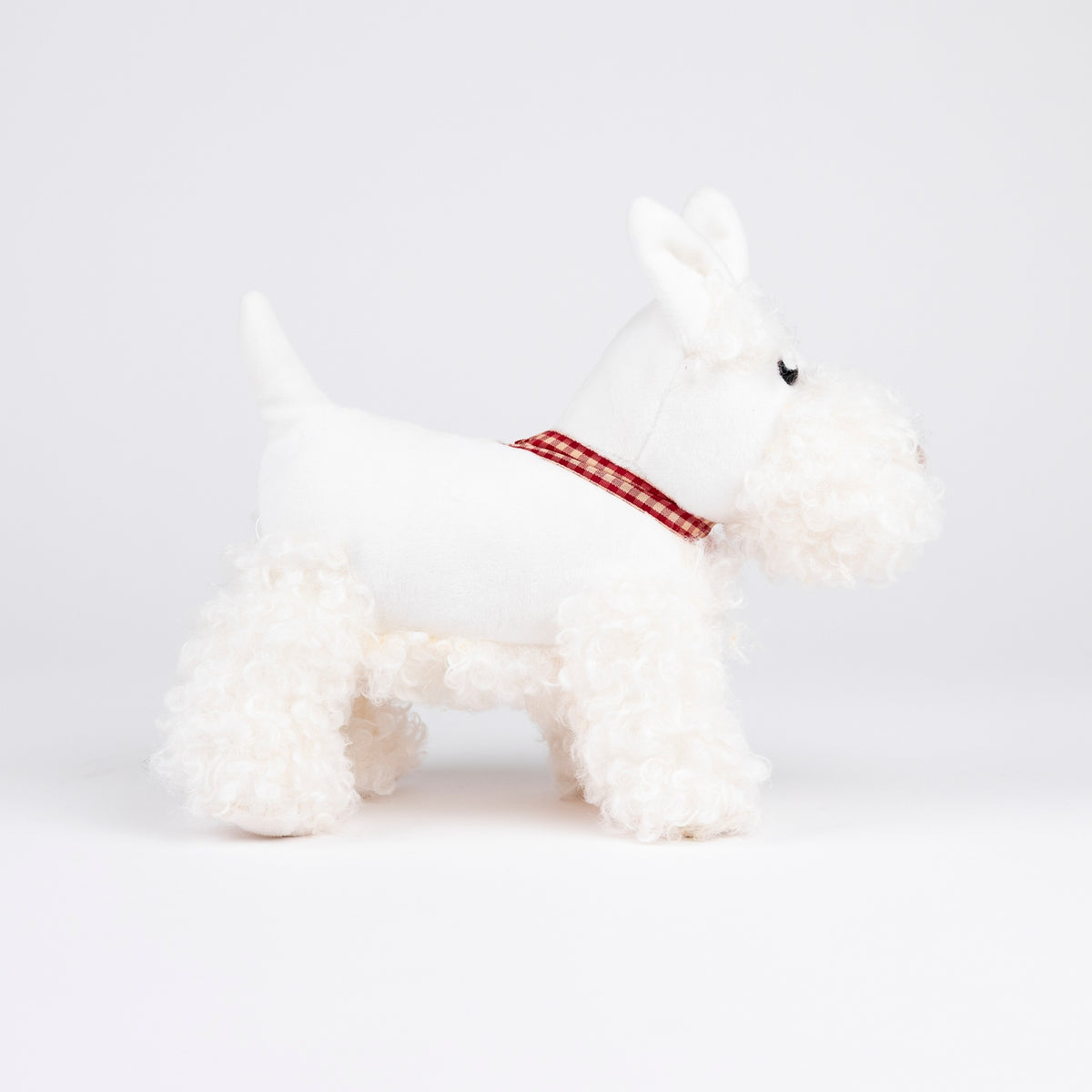 White plush dog toy with a red checkered ribbon on a white background