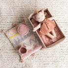 Doll in a box with a soft pillow on a textured surface