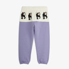 A pair of children's colorblock sweatpants in lavender and cream, featuring a white waistband with three black panther motifs.
