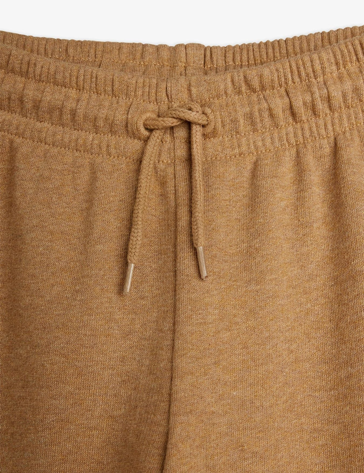 Close-up of a pair of knit lounge pants in a warm camel brown color, showing the elastic waistband and matching drawstring.