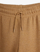 Close-up of a pair of knit lounge pants in a warm camel brown color, showing the elastic waistband and matching drawstring.