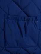 Close-up of a quilted navy blue puffer jacket showing a diamond-stitched pattern and a front pocket with an elasticated opening.