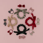 Collection of hair accessories including bows, scrunchies, and headbands on a pink background
