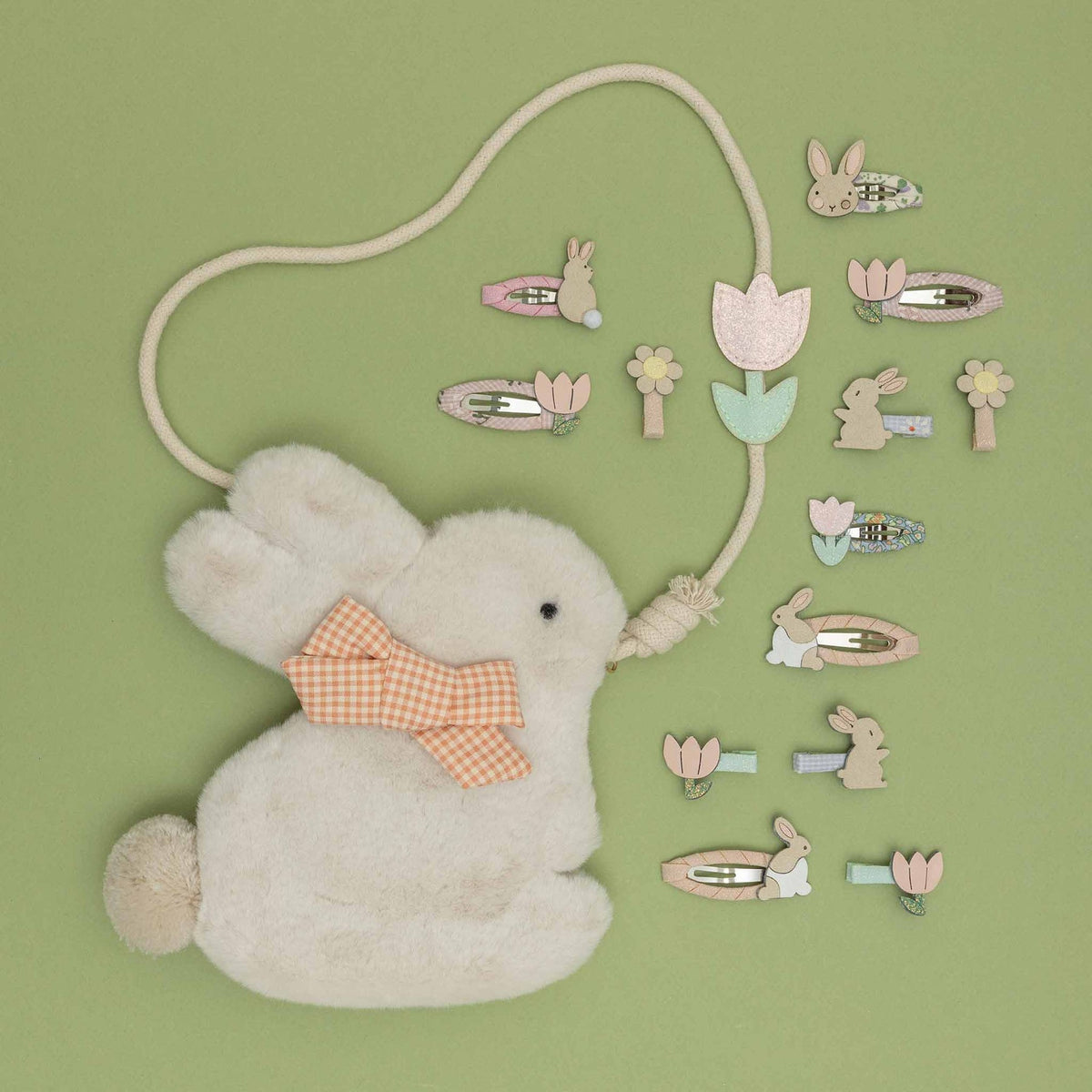 White bunny with a bow tie and a set of decorative hair clips on a green background