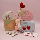 Set of children's accessories including a small bag, mirror, and heart-shaped items on a pink background