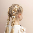 Child with braided hair adorned with floral hair clips on a beige background