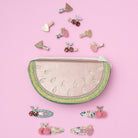 Set of decorative hair clips and a decorative pouch on a pink background