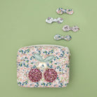 Four floral bow hair clips and floral pouch bag on a green background