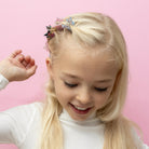 Young girl with blonde hair and blue eyes against a pink background