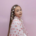 Young girl with decorative hair clips against a pink background