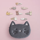 Collection of cat-themed hair clips and a cat-shaped pouch on a pink background