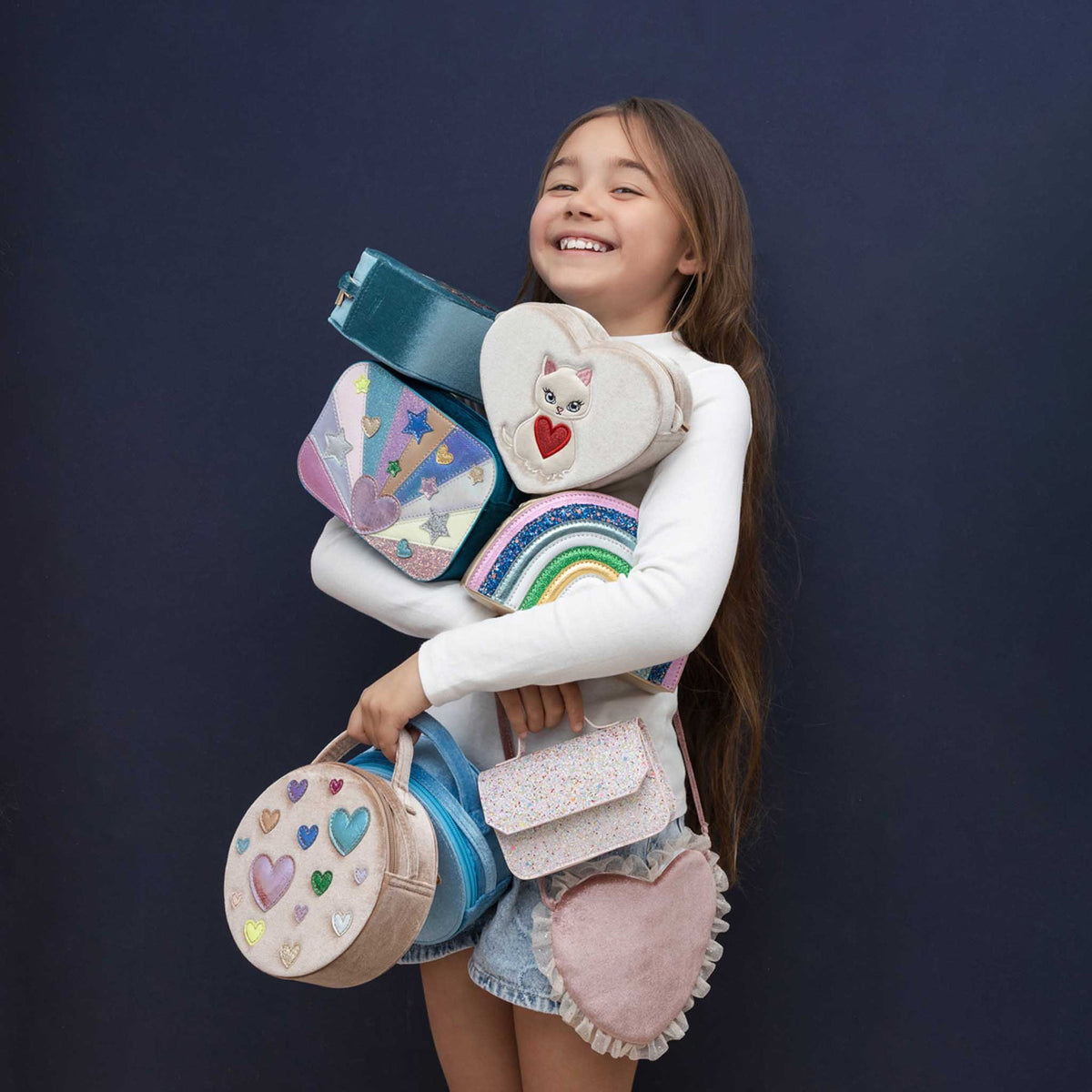 Girl holding colorful pouches against a dark background