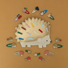 Hedgehog-shaped hair clip holder with various colorful hair clips on a brown background