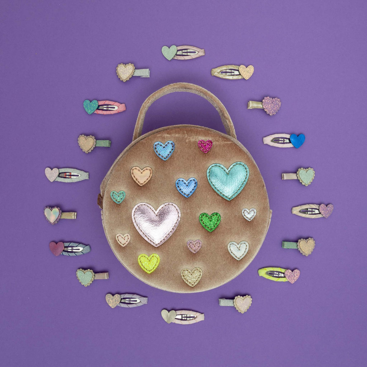 Round brown bag with heart-shaped decorations surrounded by colorful heart-shaped hair clips on a purple background