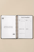 Open daily tracker notebook on a beige background