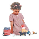 Child in a red checkered dress playing with toy farm animals on a white background