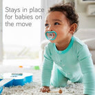 Baby on a blanket with a green pacifier, text '100% Soft Silicone' below.