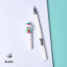 A white gel pen with a cute cupcake character on the cap, placed next to an open lined notebook on a teal background. The brand name 'Sprey' is printed on the pen barrel, and the text 'BLACK' appears in the bottom left corner.